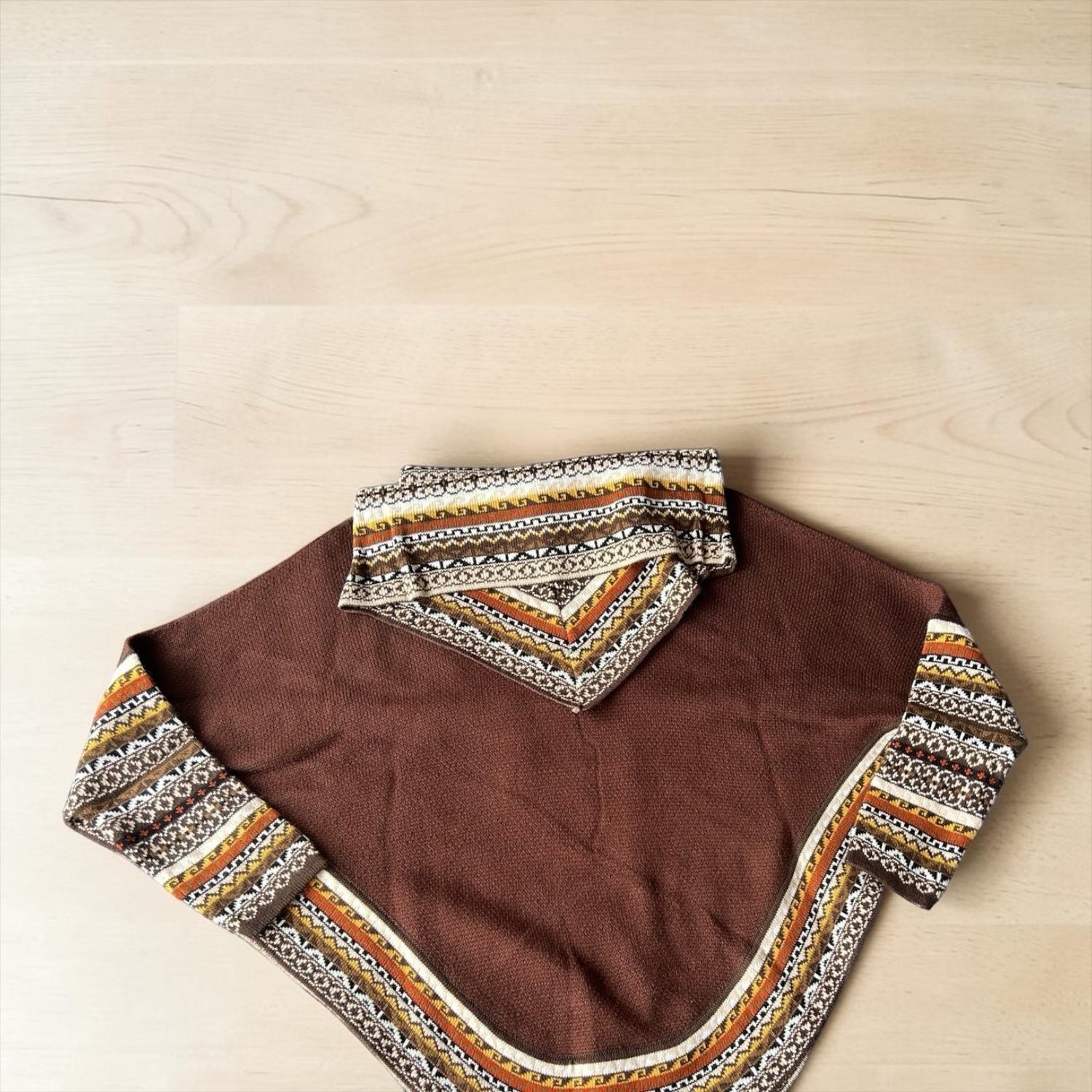 Peruvian Accent brown alpaca poncho with sleeves featuring a geometric pattern on the collar and cuffs.