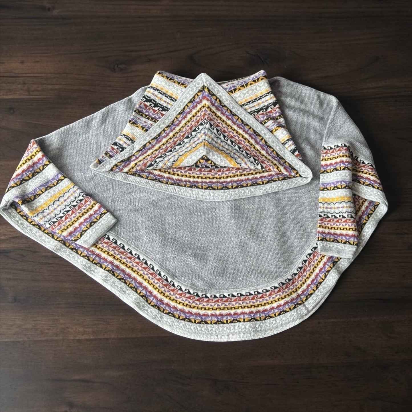 Peruvian Accent grey alpaca poncho with sleeves featuring a colorful geometric pattern on the collar and cuffs.