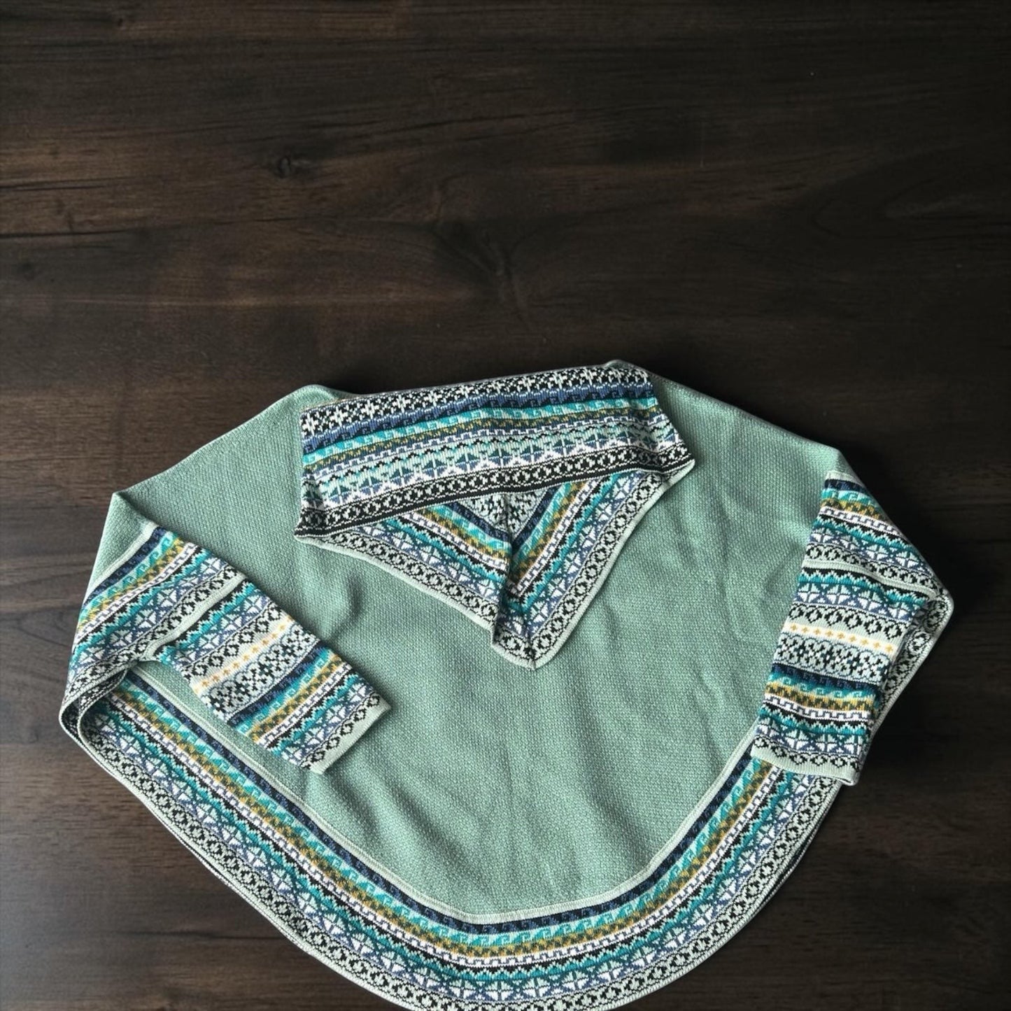 Peruvian Accent light green alpaca poncho with sleeves and cowl neck featuring a geometric pattern in blue, white, and yellow.