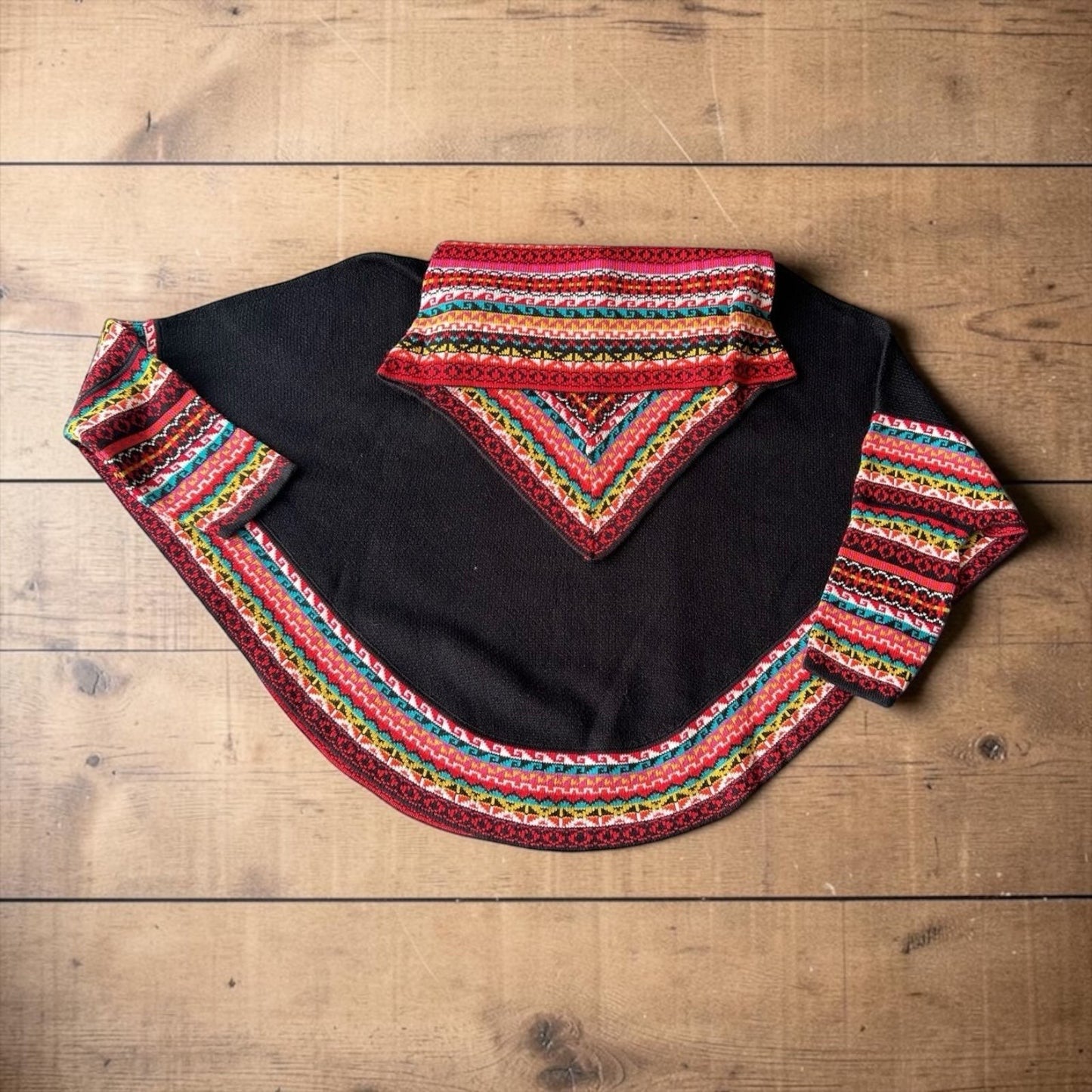 Peruvian Accent black alpaca poncho with sleeves and colorful geometric trim, featuring a cowl neck.