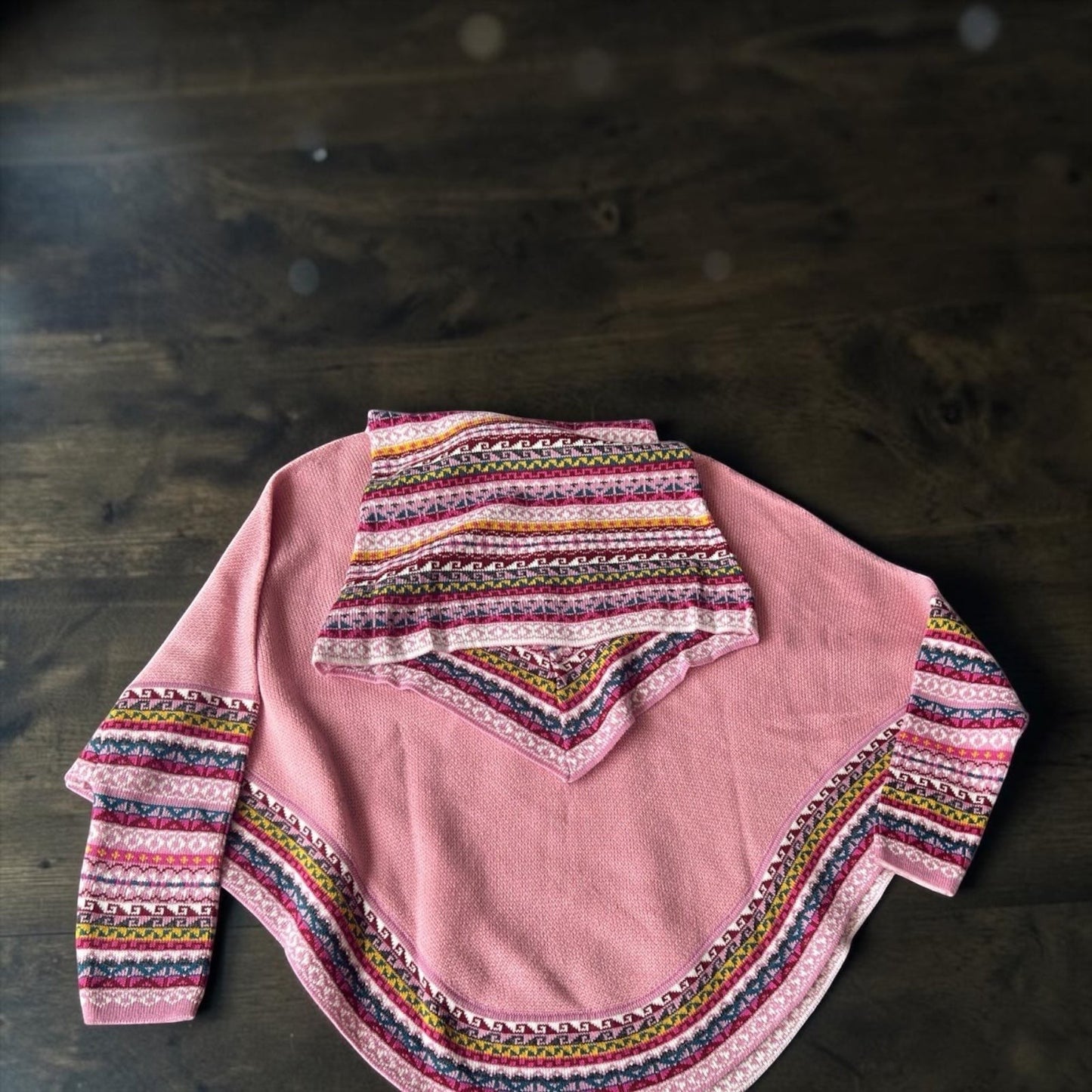 Peruvian Accent pink alpaca poncho with sleeves and cowl neck, featuring a colorful geometric pattern trim.