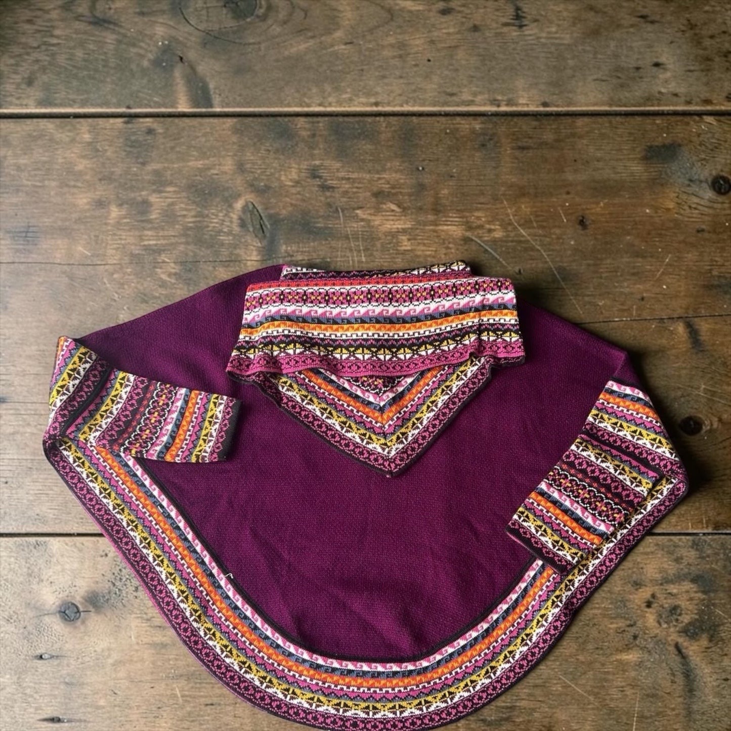 Peruvian Accent plum alpaca poncho with sleeves, featuring a colorful geometric pattern trim and cowl neck. One size fits all.