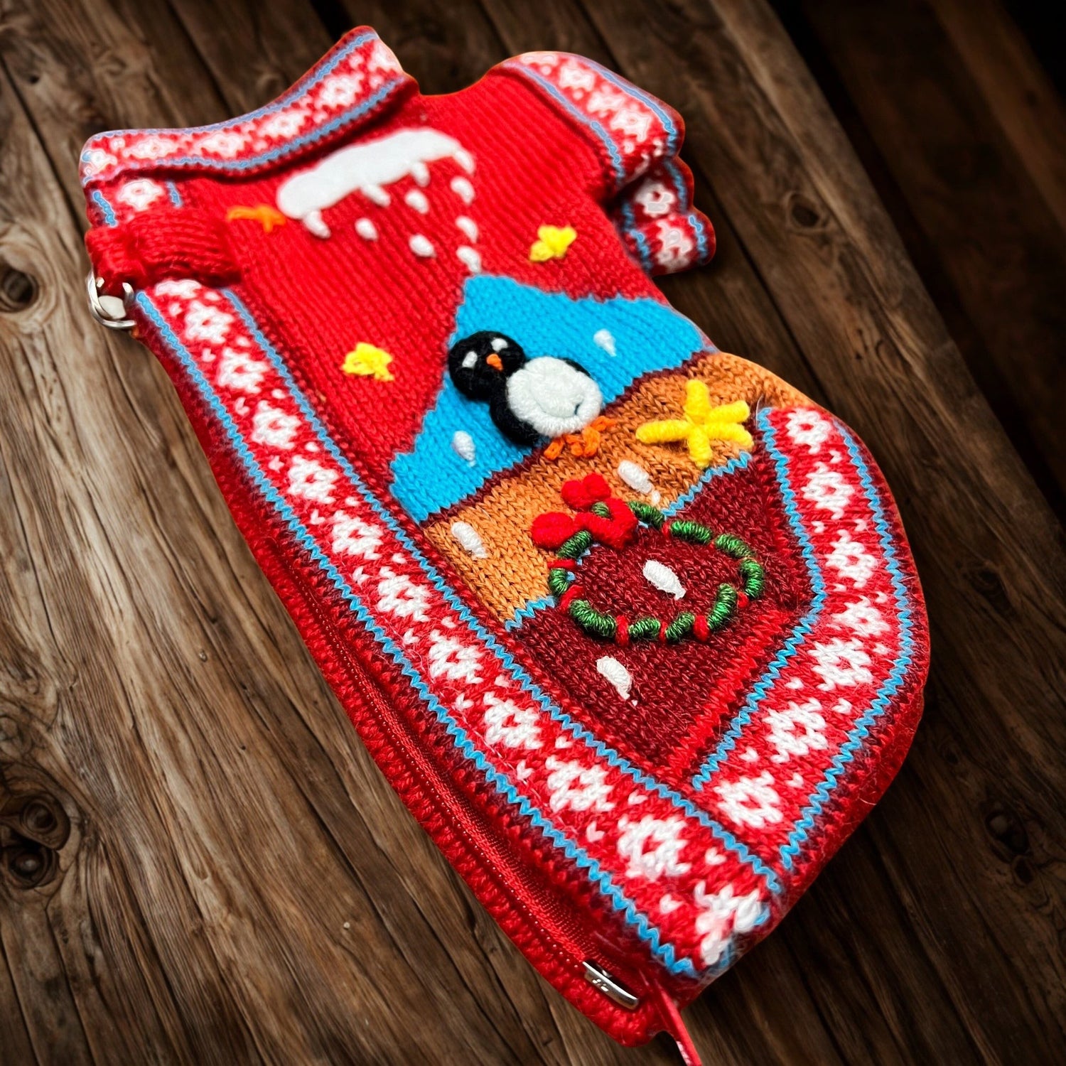 Peruvian Accent red alpaca dog sweater with penguin, mountains, and festive holiday motifs. Features a zip-up closure.
