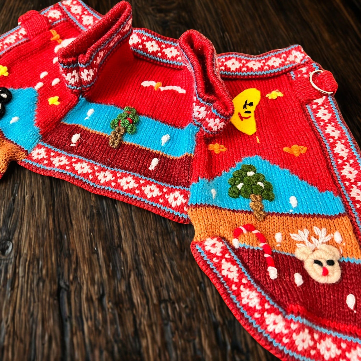Peruvian Accent red alpaca dog sweater with festive holiday scene including reindeer, candy cane, moon, and trees.