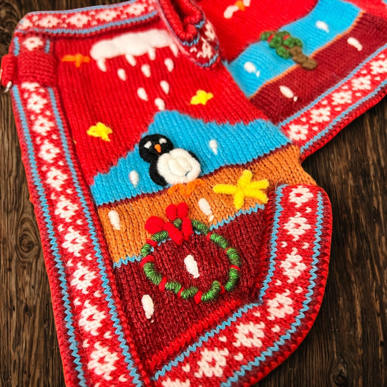 Peruvian Accent red alpaca dog sweater with winter scene, penguin, wreath, and snowflakes. Special Edition.